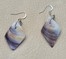 Pair of earrings with marbled design on a beige surface