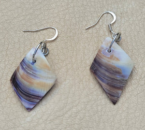 Pair of earrings with marbled design on a beige surface